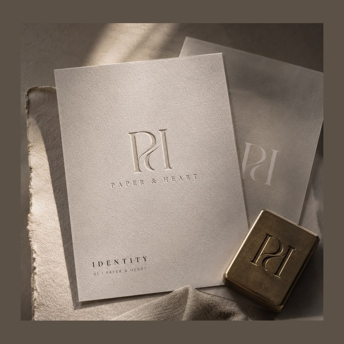 An identity folio, monogram pressed into the cover, brass stamping block alongside